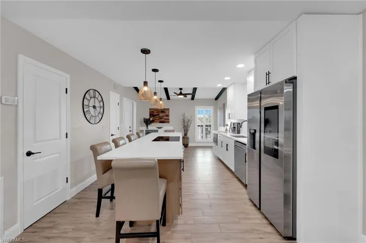Kitchen featuring a breakfast bar area, white cabinetry, appliances with stainless steel finishes, light wood-style flooring, and hanging light fixtures