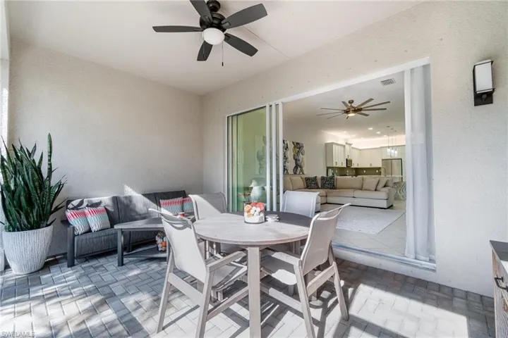 Large screened-in lanai featuring ceiling fan, brick flooring, and 3 slider door.