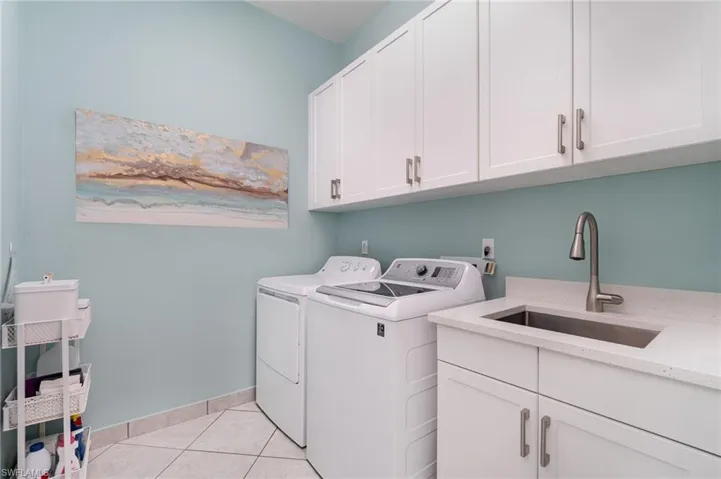 Laundry room featuring cabinet space, GE washer and dryer, laundry sink, and clothes drying rack.