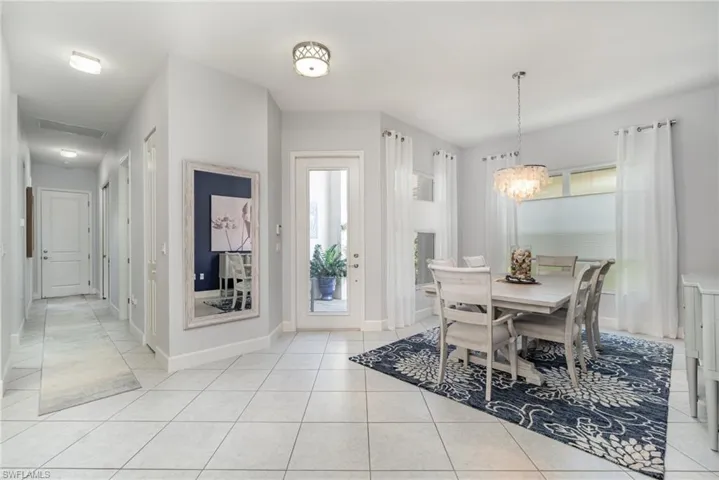 Open dining area with a chandelier and light tile flooring.