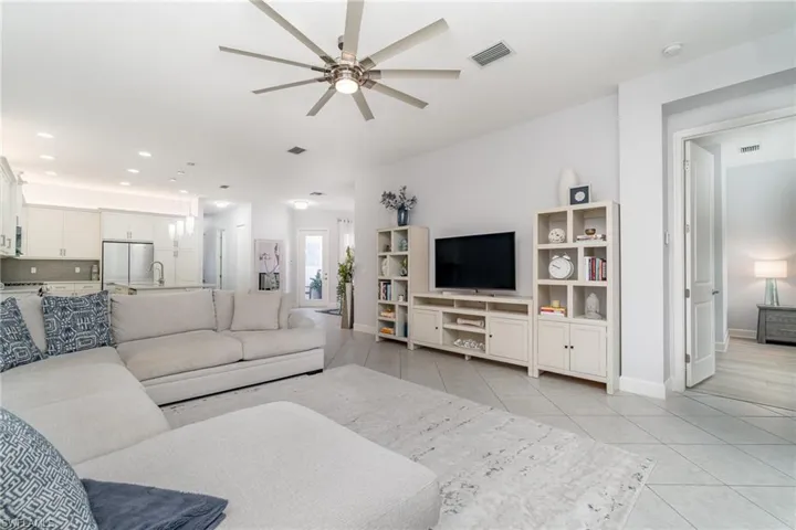 Open living room with light tile and ceiling fan.