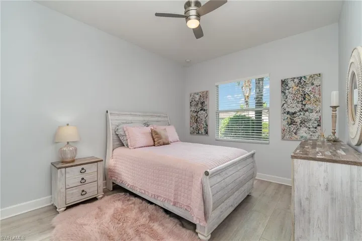 Guest bedroom with LVT flooring, walk-in closet, ensuite, and ceiling fan.