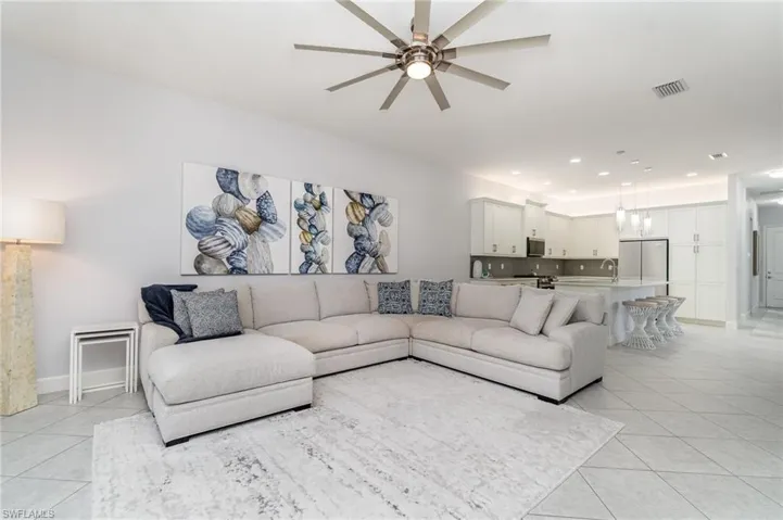 Open living area with light tile and a ceiling fan.