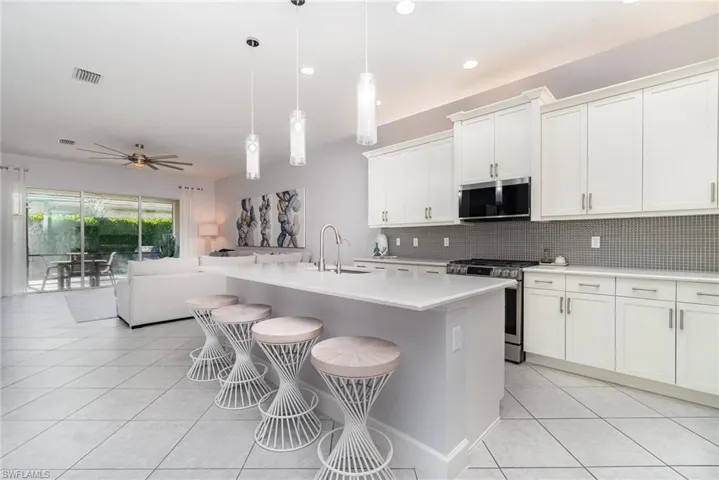 Open kitchen featuring an island with seating for four and quartz counters.