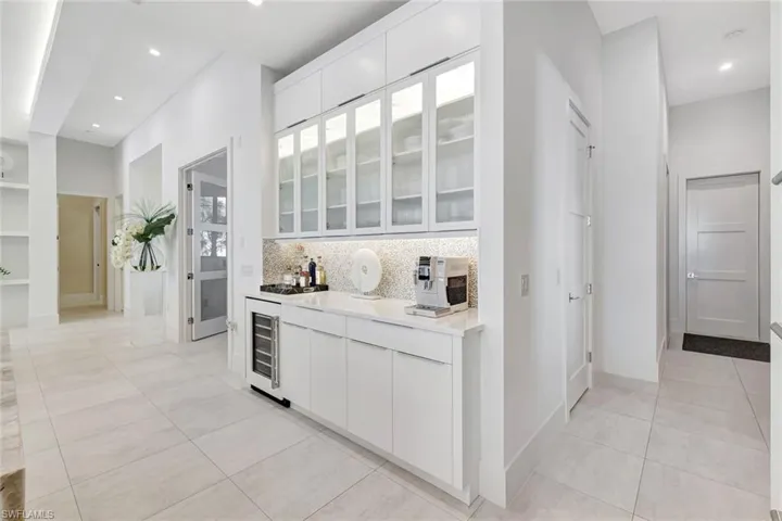 Bar area with white cabinets, glass insert cabinets, modern cabinets, light tile patterned floors, and recessed lighting
