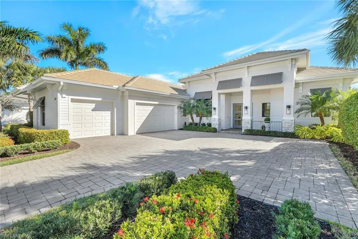 British West Indies  house with decorative driveway, a garage, a tile roof, and stucco siding