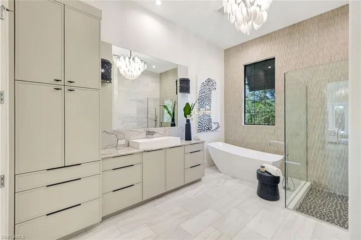 Bathroom with a chandelier, a shower stall, vanity, and a freestanding bath