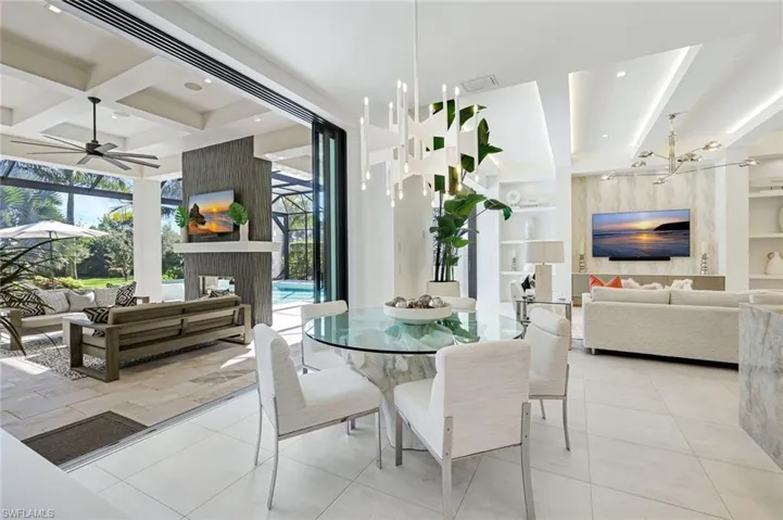Tiled dining space featuring beam ceiling, built in shelves, coffered ceiling, a sunroom, and ceiling fan