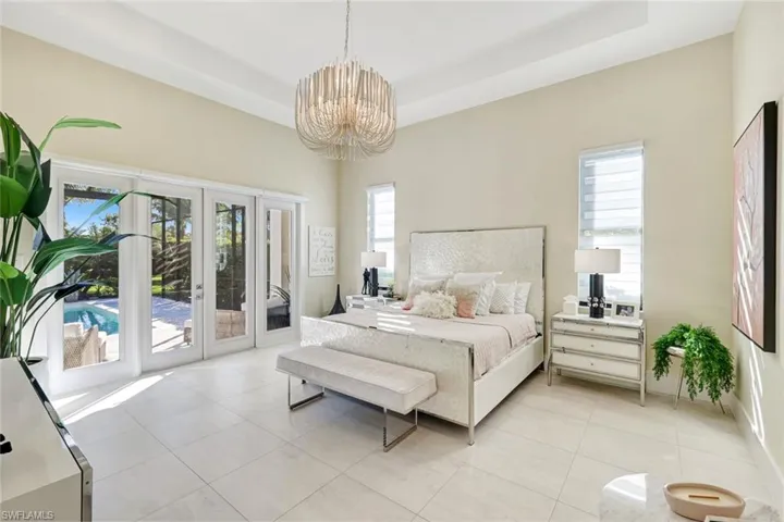 Bedroom featuring access to outside, light tile patterned flooring, a chandelier, and a raised ceiling
