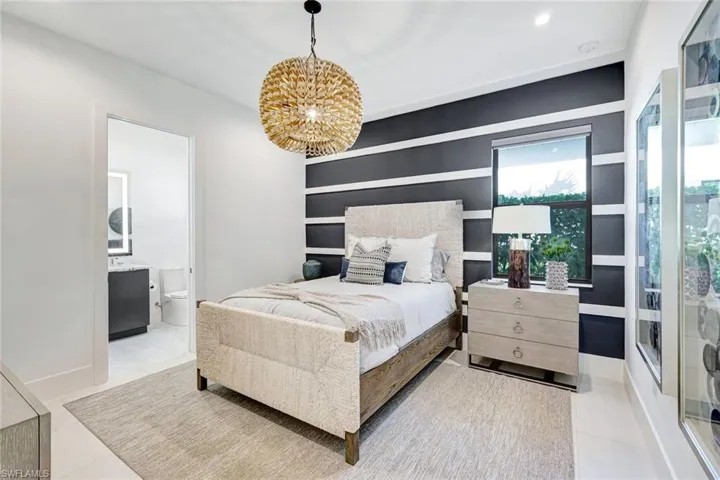Bedroom with ensuite bathroom, a chandelier, and light tile patterned floors