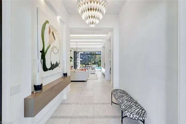 Hall with a chandelier and light tile patterned floors, custom shelf with art niche