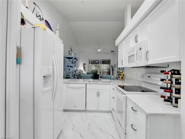 Kitchen with ceiling fan, sink, white cabinets, and white appliances