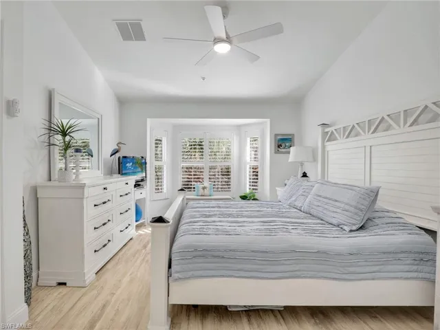 Bedroom with ceiling fan, light wood-type flooring, and lofted ceiling