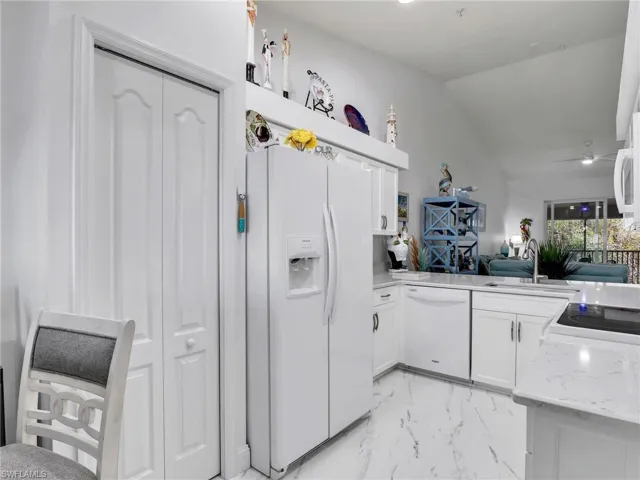 Kitchen featuring ceiling fan, vaulted ceiling, sink, white appliances, and white cabinets