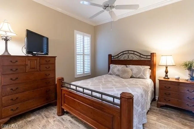 Bedroom featuring hardwood / wood-style flooring, ceiling fan, and crown molding
