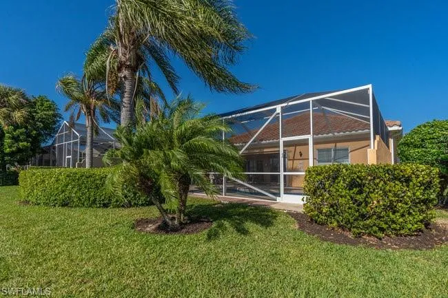 Rear view of property with a lanai and a lawn