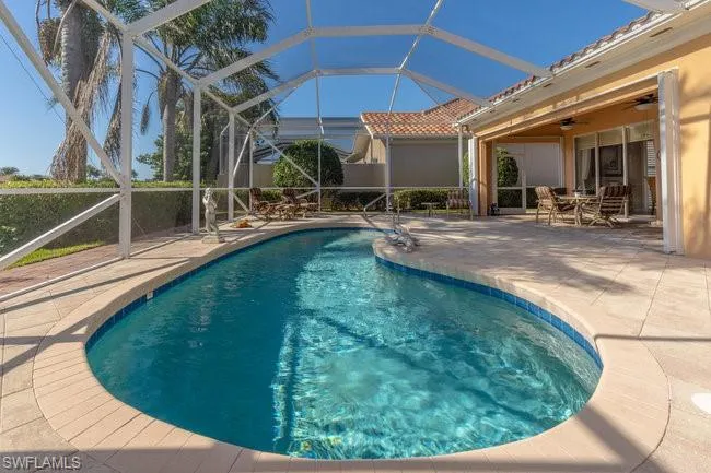 View of swimming pool with a patio area, ceiling fan, and glass enclosure