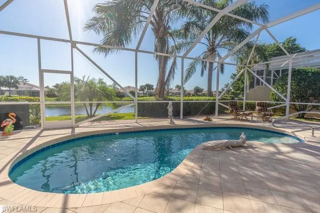 View of swimming pool featuring a patio area, a water view, and glass enclosure