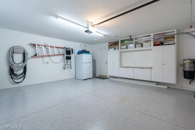 Garage featuring white fridge and a garage door opener