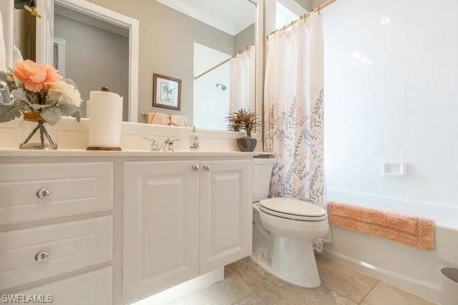 Full bathroom featuring tile patterned flooring, shower / tub combo, toilet, and crown molding