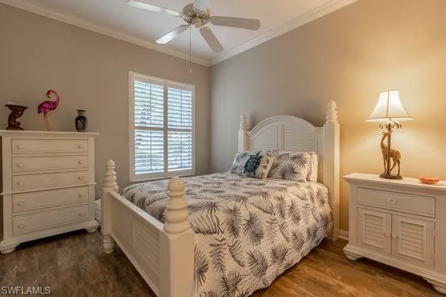 Bedroom with crown molding, ceiling fan, and dark wood-type flooring