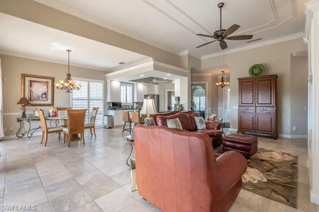 Living room featuring ceiling fan with notable chandelier and ornamental molding