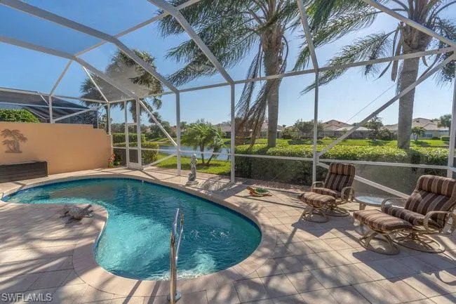 View of pool with glass enclosure and a patio area