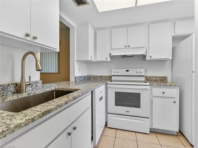 Kitchen featuring white cabinetry, speckled countertops, a stainless steel sink with a high-arc faucet, a white electric range, and tile flooring
