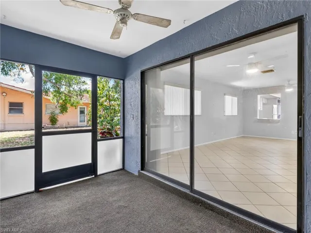 Screened patio featuring a ceiling fan, textured walls, and carpet flooring