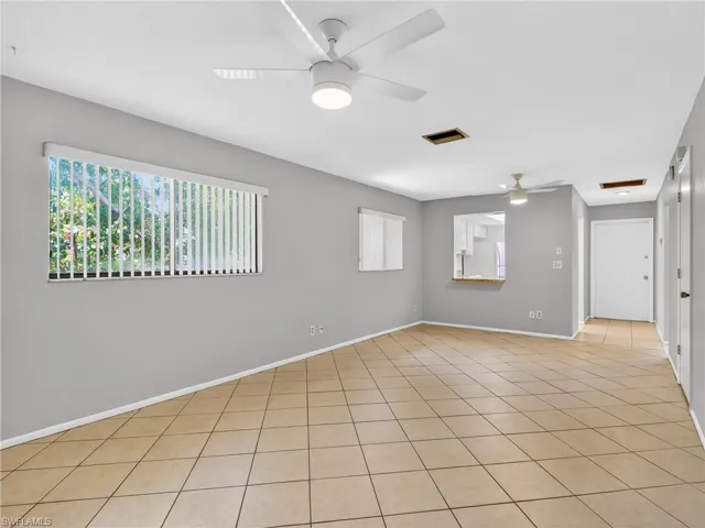 Spacious room featuring neutral-toned tile flooring, light gray wall paint, and multiple ceiling fan light fixtures