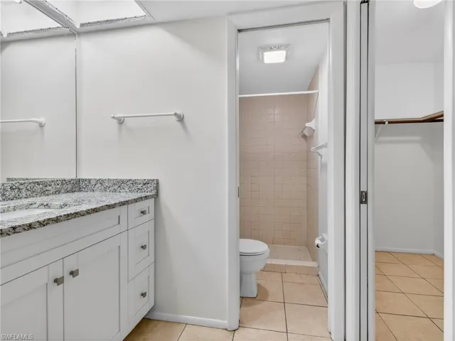 Bathroom featuring a white vanity with a patterned countertop, integrated sink, and white cabinetry