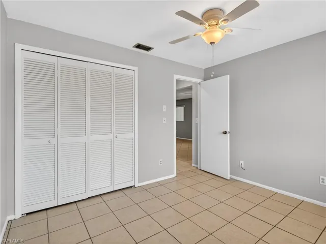 Neutral-toned tile flooring, light gray wall paint, and a ceiling fan with integrated lighting