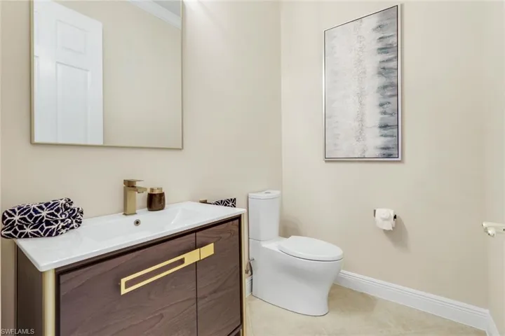 Half bath featuring vanity, crown molding, and light tile patterned flooring