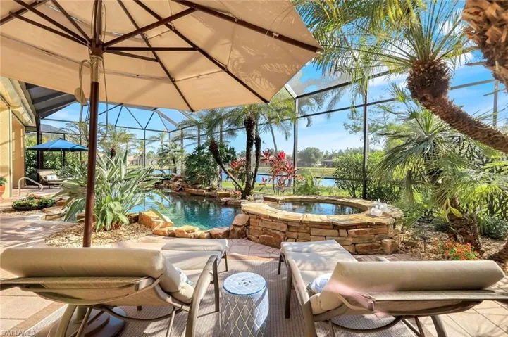 View of patio featuring a lanai, a sunroom, a water view, and a pool with connected hot tub