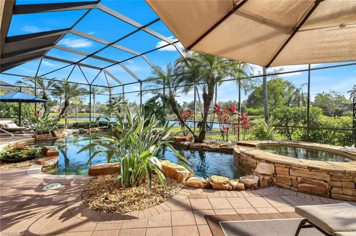 View of patio / terrace featuring a lanai, a sunroom, an outdoor pool, and an in-ground hot tub