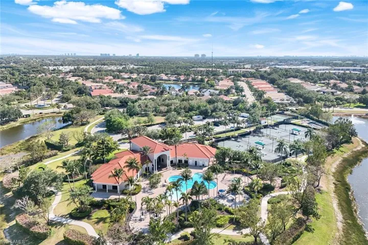Aerial view of property and surrounding area featuring a nearby body of water and a pool area