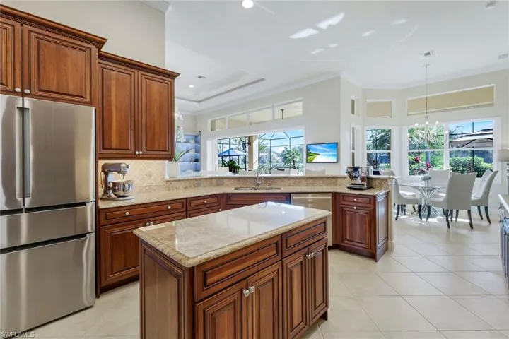 Kitchen with appliances with stainless steel finishes, a peninsula, hanging light fixtures, ornamental molding, and a center island
