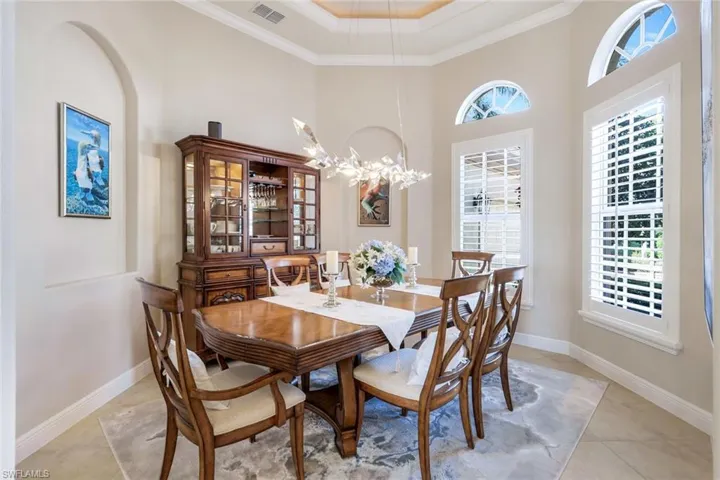 Dining room with a towering ceiling, a tray ceiling, crown molding, plenty of natural light, and a chandelier