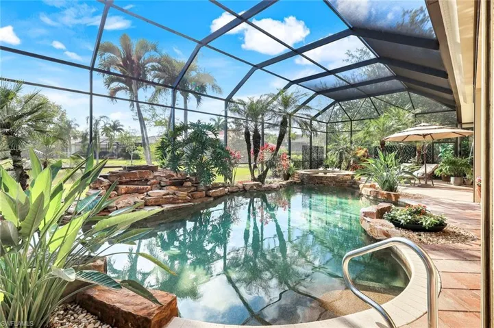 View of pool with a sunroom, glass enclosure, a patio area, and a pool with connected hot tub