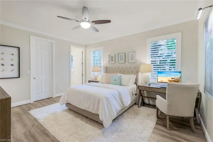 Bedroom featuring ornamental molding, a ceiling fan, multiple windows, and light wood-style floors