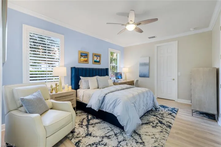 Bedroom featuring ornamental molding, light wood-type flooring, and a ceiling fan
