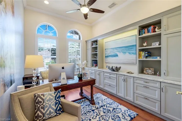 Office area with crown molding, light wood-style floors, and a ceiling fan