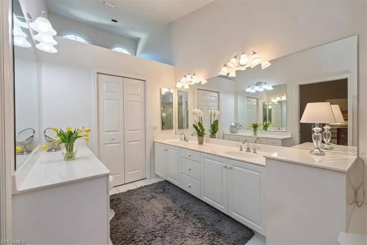 The primary bath offers dual vanities, a luxurious soaking tub, and a separate glass-enclosed shower, all opening to a spacious walk-in closet illuminated by a large window and abundant natural light.