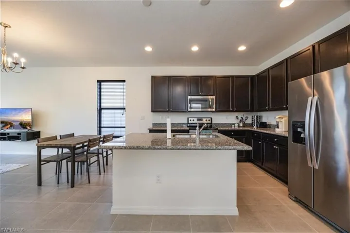 Kitchen with recessed lighting, a chandelier, a sink, stone counters, and stainless steel appliances