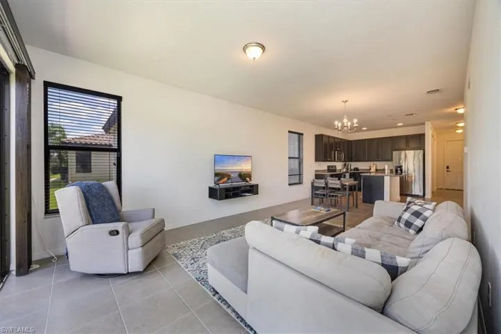 Living area with a notable chandelier, light tile patterned floors, and visible vents