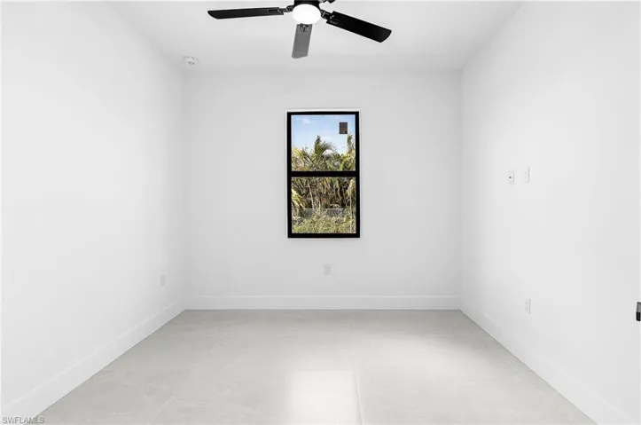 Empty room with ceiling fan and light tile patterned flooring