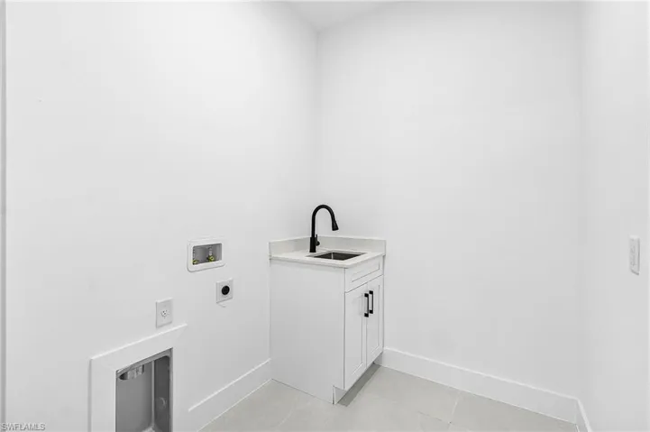 Laundry area with cabinet space, hookup for a washing machine, hookup for an electric dryer, and light tile patterned flooring
