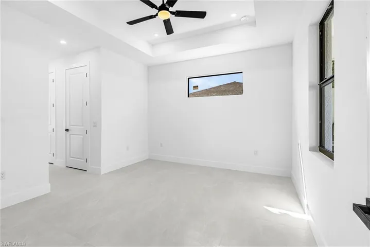 Empty room featuring a ceiling fan, a tray ceiling, and recessed lighting