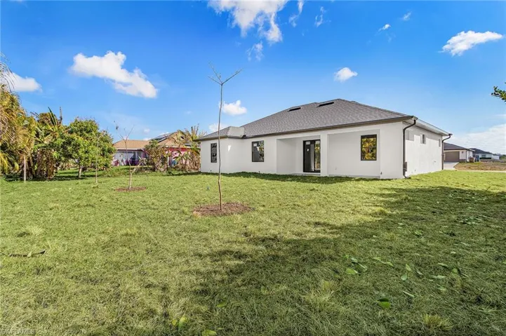 Back of property with stucco siding and a yard