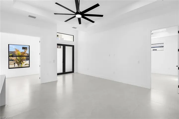 Spare room featuring ceiling fan, a high tray ceiling, and plenty of natural light